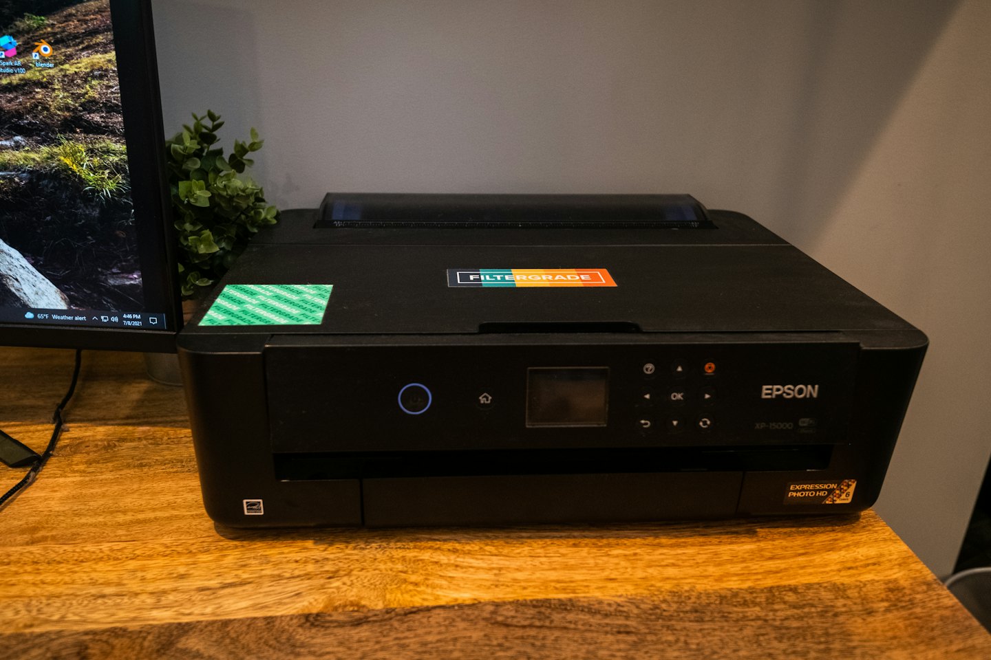 Schwarzer Epson Drucker und Computermonitor auf einem Holztisch.