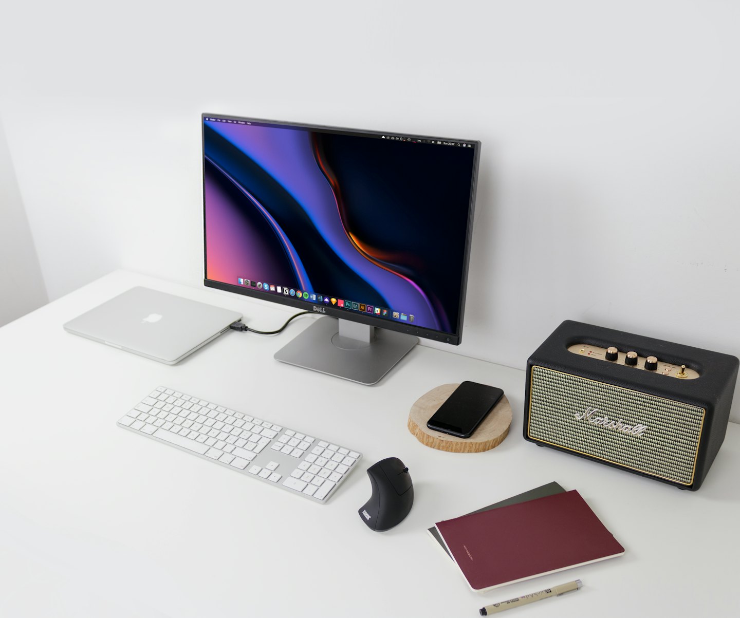 Moderner Schreibtisch mit Laptop, Monitor, Tastatur und Lautsprecher.